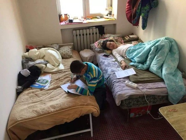 Cậu bé vừa học bài, vừa chăm sóc mẹ.