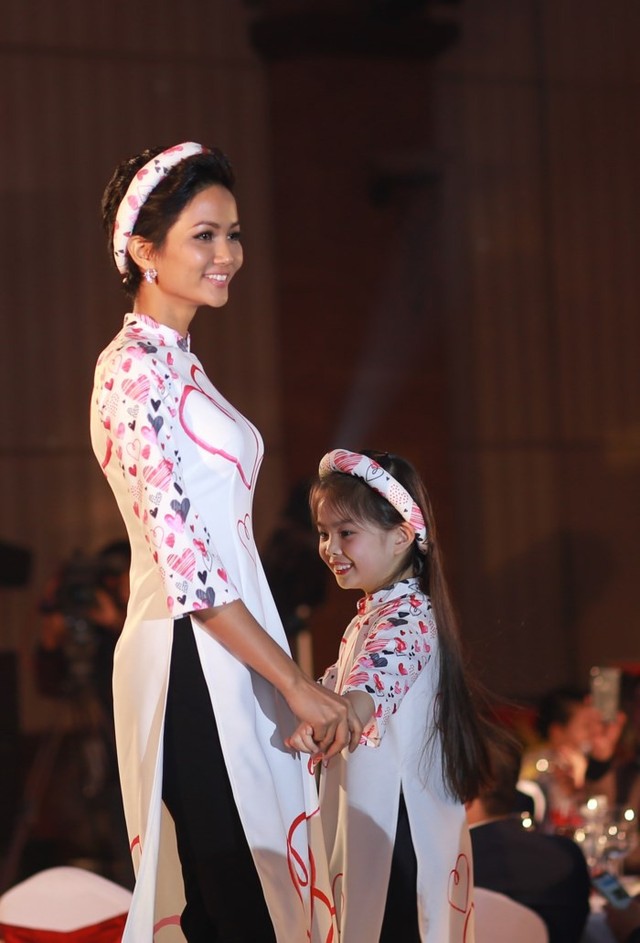 H’Hen Niê diện áo dài họa tiết trái tim, tự tin trình diễn catwalk cùng với người mẫu nhí trong chương trình.