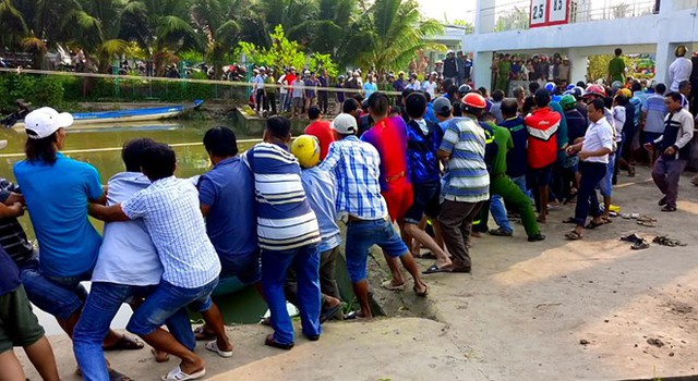 Hơn trăm người k&eacute;o hai nắp cống để cứu nạn nh&acirc;n. Ảnh: Nhật T&acirc;n.