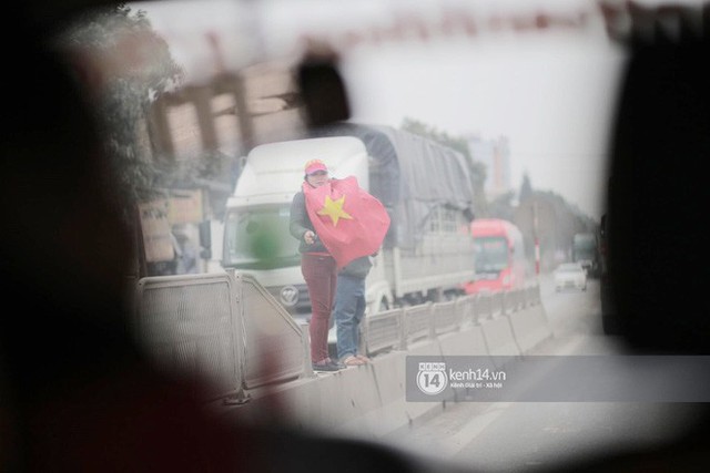 Một người phụ nữ mang theo cờ Tổ  quốc chờ đón các cầu thủ về quê nhà Thanh Hóa. Ảnh: Mai Lân