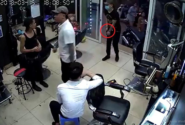 Hình ảnh nhóm đối tượng vào trong quán cắt tóc, một đối tượng đeo khẩu trang móc trong túi ra một vật nghi là súng để bắn nam nhân viên (Ảnh: Cắt từ clip).
