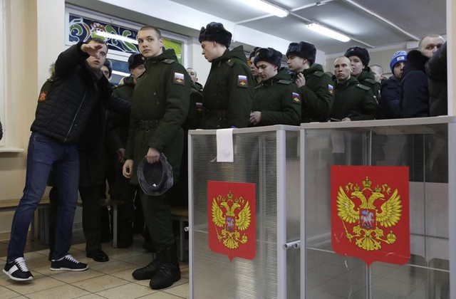 Quân nhân Nga xếp hàng chờ được hướng dẫn bỏ phiếu tại một điểm bầu cử ở St. Petersburg. Ông Putin, 65 tuổi, sẽ tại vị thêm 6 năm nữa nếu giành chiến thắng.
