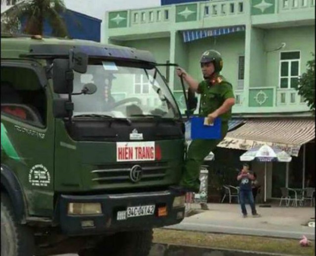 
Chiến sĩ công an trật tự đu gương trên xe ô tô tải vi phạm. Ảnh: Cắt từ clip
