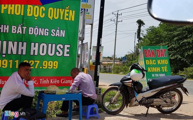 Nhân viên tiếp thị đất dựng pa nô, che dù ngoài vỉa hè để rao bán đất.