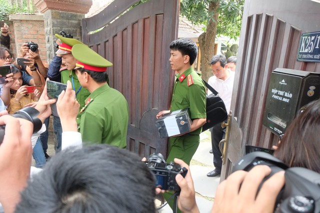 
Lực lượng Công an đi từ trong nhà ông Minh ra xe, kèm theo tài liệu niêm phong.
