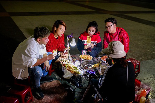 Các nghệ sĩ trẻ hào hứng thưởng thức món bánh tráng nướng hay còn gọi là pizza Việt Nam ở lề đường.