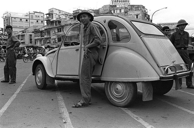 Một người lính đứng bên cạnh một chiếc xe hơi tại vòng xoay Quách Thị Trang vào ngày 30 tháng 4 năm 1975