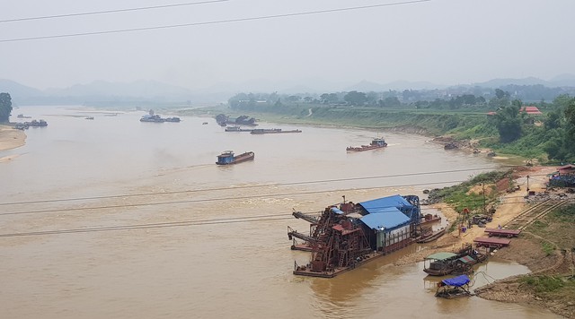 
Đứng từ cầu An Hòa có thể thấy cả chục chiếc tàu cỡ lớn đang khai thác cát dưới dòng sông Lô.
