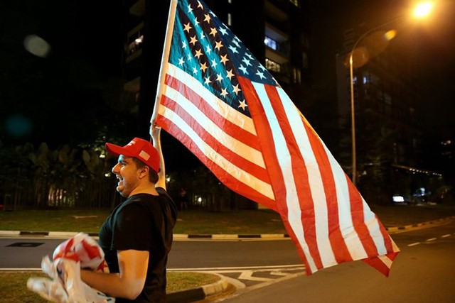 Một người ủng hộ vẫy cờ Mỹ trên đường Anderson, nơi đoàn xe của ông Trump đi qua.