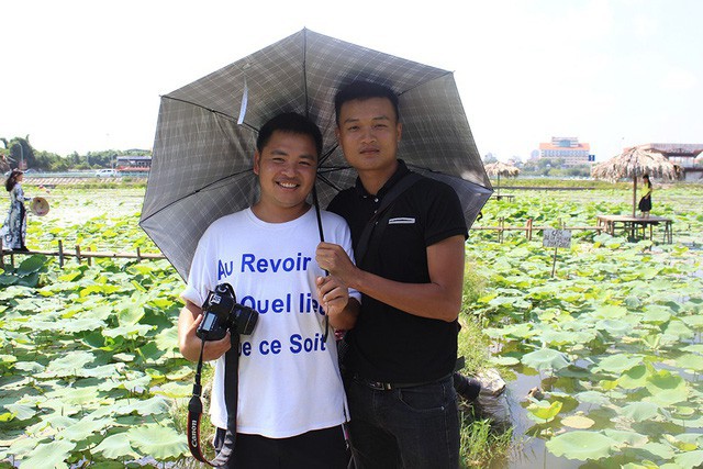Phó nháy Nguyễn Minh Tiến (phải) mỗi ngày kiếm từ 1,5 - 2 triệu đồng nhờ nghề chụp ảnh cho khách tại đầm sen Hồ Tây.