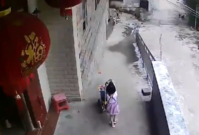 B&eacute; g&aacute;i đứng b&ecirc;n xe đẩy chở em trai trước khi thả tay ra. Ảnh cắt từ video.