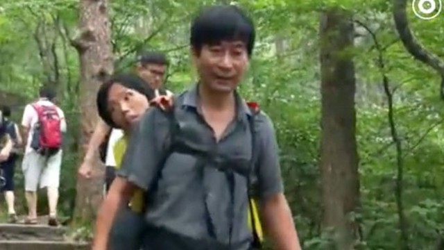 Ông Wang cõng vợ từ trên đỉnh Huangshan, tỉnh An Huy, xuống chân núi hôm 23/7. Ảnh: SCMP.