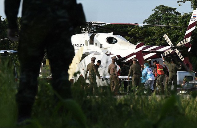
Cậu bé thứ 5 được che chắn bằng ô trắng khi xuống trực thăng bằng cáng. Ảnh: AFP
