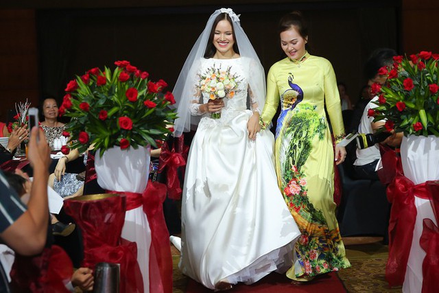 
Mẹ c&ocirc; d&acirc;u&nbsp;(phải) dắt con g&aacute;i l&ecirc;n s&acirc;n khấu l&agrave;m lễ.&nbsp;
