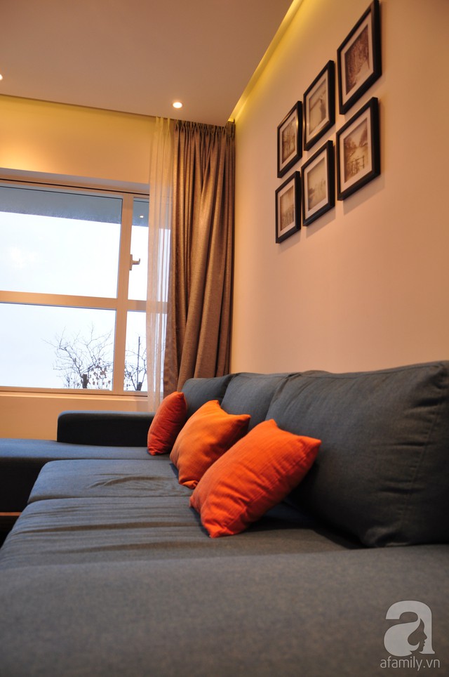 Sofa màu xanh xám được tạo điểm nhấn bằng gối tựa và tranh treo tường.