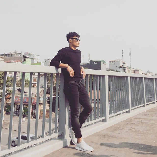 Chàng thủ môn mặc áo dệt kim và quần ôm màu đen kết hợp với giày thể thao.