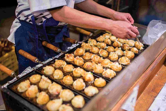 Takoyaki: Được gọi nôm na là những quả bóng bạch tuộc, món ăn này có hành lá, gừng ngâm, bột chiên giòn tenkasu, rong biển và những miếng bạch tuộc nhỏ. Phần topping ăn kèm tương tự món okonomiyaki, song takoyaki nóng chảy bên trong, vì vậy bạn cần chú ý để tránh bỏng lưỡi khi cắn vào. Ảnh: Intrepid Travel.