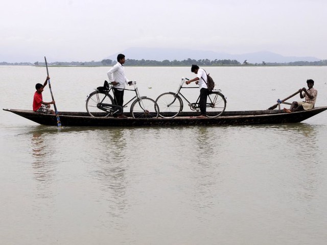 Mưa lớn có thể làm ngập ruộng lúa, buộc học sinh quận Morigaon ở đông bắc Ấn Độ không thể đạp xe dễ dàng như ngày thường.