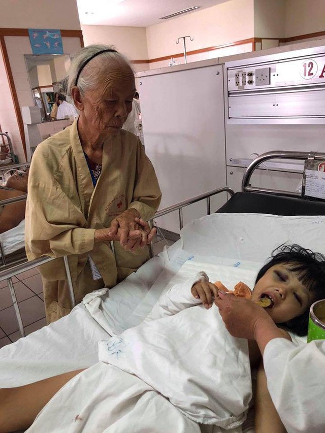 Bé Thu Trâm được cụ Cẩm 78 tuổi chăm sóc trong bệnh viện. Ảnh: Uyển Hương