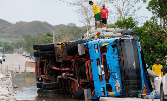 Các công nhân chuyển những bao tải ngũ cốc từ xe tải bị bão quật đổ ở phía bắc Philippines hôm 16/9.