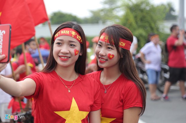 Hai CĐV xinh đẹp, mặc áo đỏ sao vàng, đeo băng C chụp ảnh selfie chờ Đoàn TTVN. Ảnh: Zing.vn
