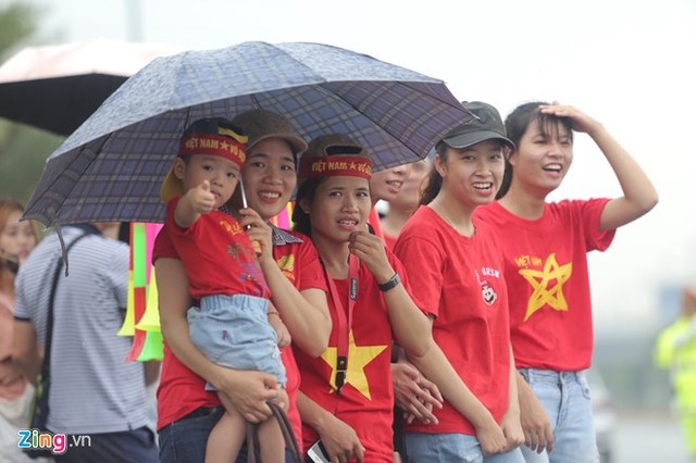 Bất chấp trời mưa, nhiều người hâm mộ diễu hành, đội ô chờ đoàn trước cổng sân bay Nội Bài. Ảnh: Zing.vn