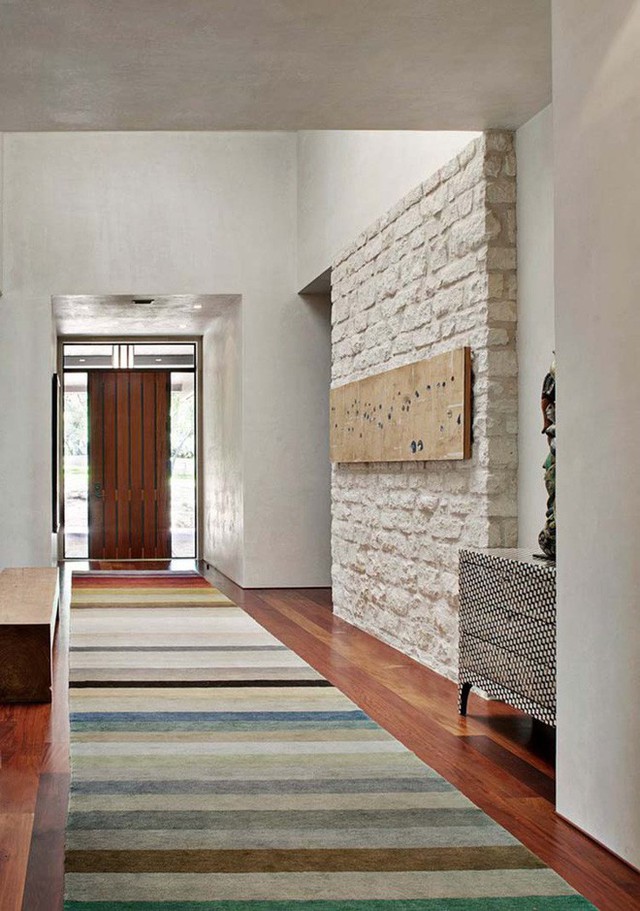 Một hành lang dẫn vào nhà khá dài được sử dụng thảm trải sàn tường ốp gạch thô để tạo điểm nhấn.