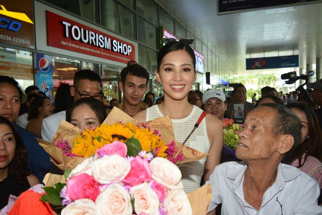 Tiểu Vy tươi tắn bên ông nội, trong lúc bạn bè và khán giả vây quanh tân hoa hậu. Ông nội cho biết rất vui mừng vì hoa hậu vẫn khỏe mạnh, rạng rỡ dù trong mấy ngày qua, cô phải tham gi nhiều hoạt động và thường xuyên xuất hiện trước truyền thông. Ảnh: BTC.