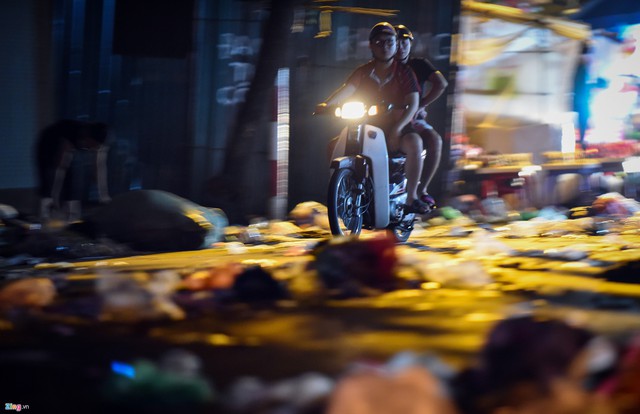 Người đi xe máy ngang qua phố Hàng Mã phải tránh những đống rác lớn ngay giữa đường.