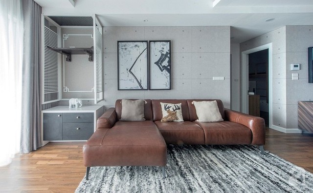 Phòng khách được thiết kế đơn giản với giấy dán tường màu ghi. Sofa da trở thành điểm nhấn sang trọng.