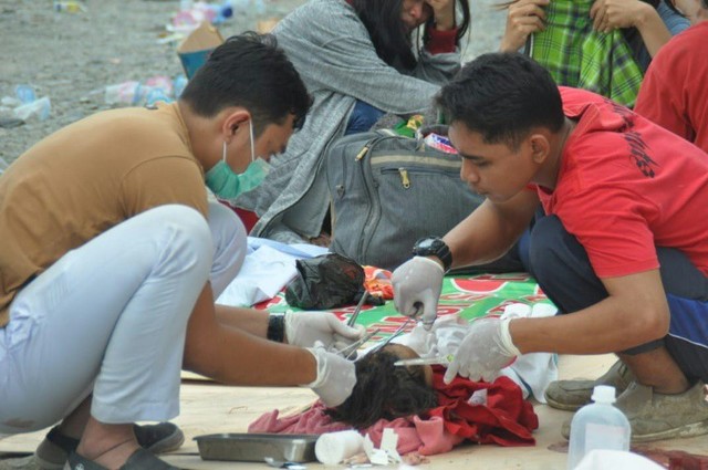 Một nhân viên y tế điều trị cho nạn nhân sống sót ở ngoài một bệnh viện tại khu vực Donggalo, thuộc đảo Sulawesi (Indonesia) vào ngày 28.8.2018.