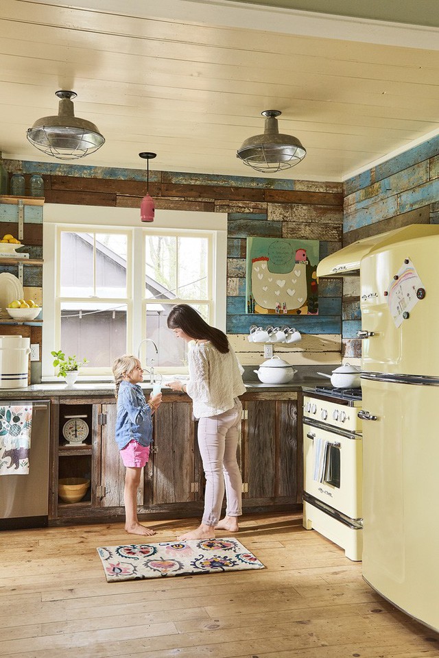 Phòng bếp được trang trí từ pallet cũ. Hệ thống tủ bếp và điểm nhấn trên tường ốp gỗ đều do tự tay người mẹ trẻ đảm nhận.