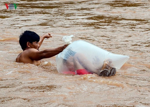 Học sinh chui vào túi nilon để người lớn đưa qua suối. (Ảnh: VOV)