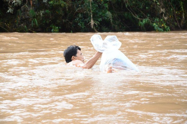 Trưởng bản Vừ A Giống đang đưa một học sinh vượt lũ bằng túi (Ảnh: Đ. Tuấn).