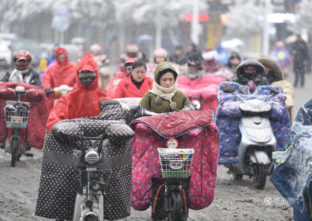 Vì tuyết rơi dày, nhiệt độ giảm thấp hôm 4/1, nhiều phụ nữ ở thành phố Hoài An, tỉnh Giang Tô phải trang bị cả áo bông dày che chắn tay chân giống như đắp chăn khi ra đường. Ảnh: QQ.