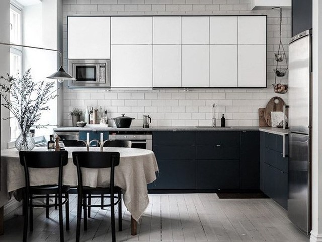 Trong không gian nhà bếp, đồ nội thất bằng gỗ màu xám trắng và tối, tủ lạnh bằng thép không rỉ, đồ dùng ăn tối màu đen, sàn gỗ, bàn làm bằng đá màu xám.