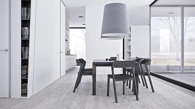 Một bộ ghế phong cách Scandinavia và bàn ăn là những đồ có màu tối nhất trong phòng. Hai chiếc đèn mặt dây chuyền màu xám khổng lồ tạo thêm sự bất cân xứng khác lạ cho căn phòng.