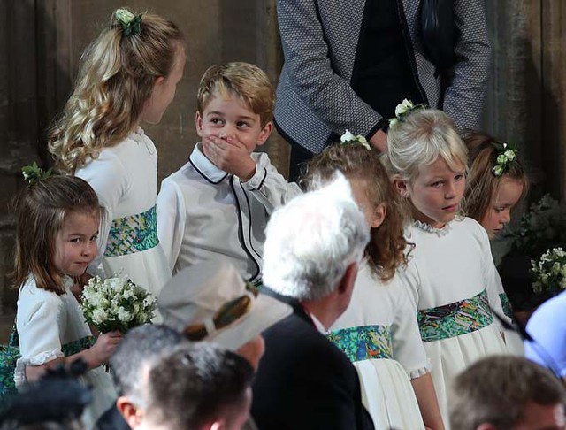 Hoàng tử George lấy tay bịt miệng khi đứng cạnh chị họ Savannah Phillips và dàn phù dâu, phù rể nhí trước khi hôn lễ trong nhà thờ của Công chúa Eugenie diễn ra.