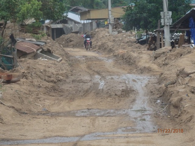 
Con đường vào bản bị phá hủy, nhiều đoạn còn ngập trong bùn đất và bãi đất trống trước kia là nhà với những gì còn sót lại sau lũ.

