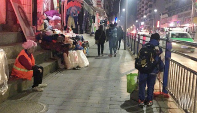 Guotao qu&eacute;t dọn vệ sinh trong khi mẹ ngồi nghỉ sau ng&agrave;y d&agrave;i mệt nhọc. Ảnh: Weibo.