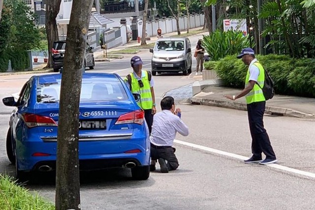 Tài xế taxi Singapore quỳ gối xin tha khi bị phạt vì hút thuốc lá - Ảnh 1.