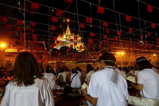 Nhiều tín đồ Phật giáo tập trung tại Chùa Vàng ở Bangkok để cầu nguyện bình an trong năm mới. Những sợi dây buộc trên đầu là một phần nghi lễ cầu nguyện. Ảnh: Reuters.