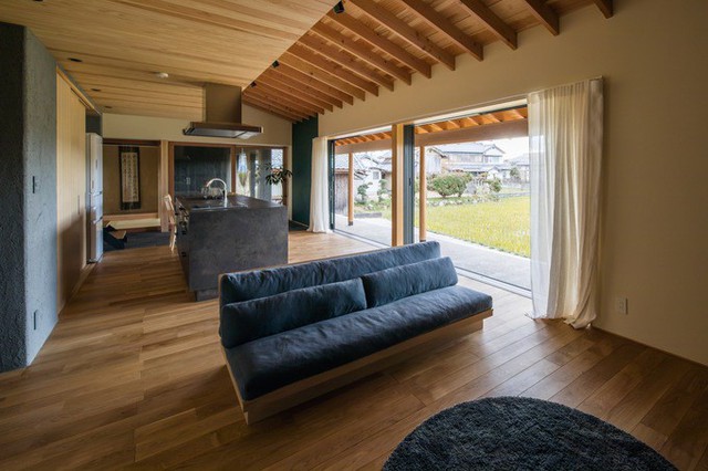 Phòng khách gần như trống trơn với chiếc ghế sofa và một tấm thảm thể hiện rõ phong cách tối giản.