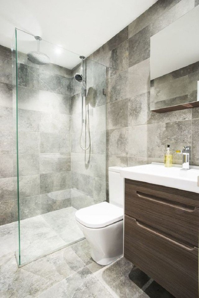 
Một đơn vị phòng tắm tinh xảo với ngăn kéo bằng gỗ và một tủ lưu trữ phù hợp với các bức tường màu xám và gạch lát sàn.
