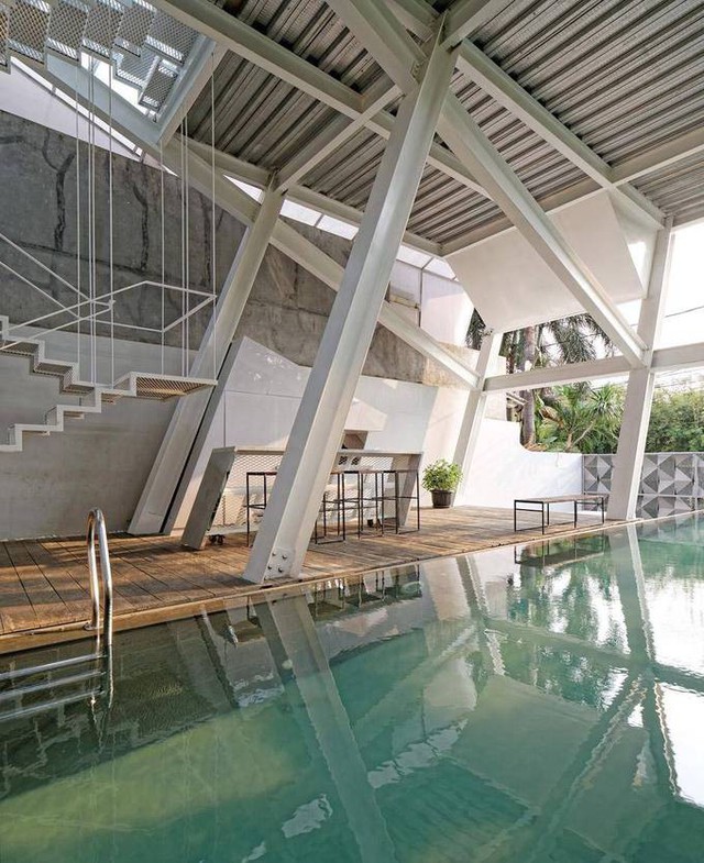 Hồ bơi nằm ngay tầng một. Hệ kết cấu ngả của ngôi nhà rọi xuống mặt bể bơi, phản chiếu sự khác lạ của thiết kế.