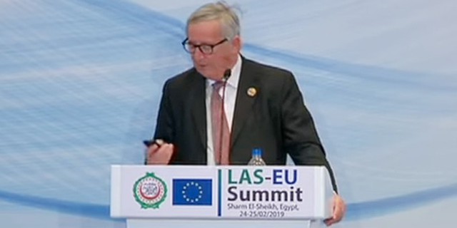 Ông Juncker bấm nghe điện thoại trong khi đang phát biểu tại hội nghị ở Ai Cập hôm 25/2. Ảnh cắt từ video.