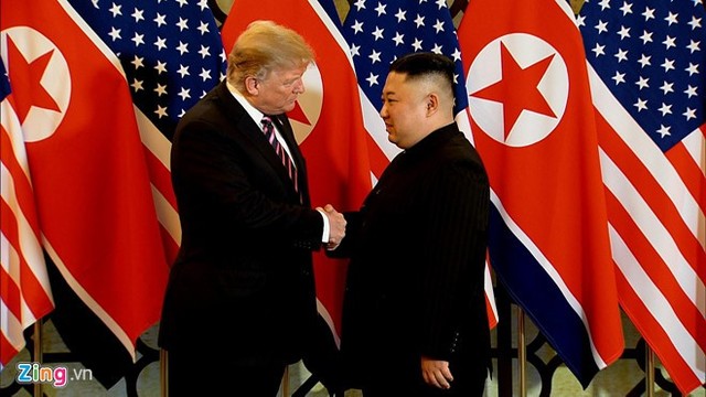 Tương tự lần gặp trước, tổng thống Mỹ và nhà lãnh đạo Triều Tiên bước ra từ hai phía của sân khấu và bước đến bắt tay nhau, tươi cười, phía sau là cờ hai nước xếp xen kẽ. Cả hai bắt đầu cuộc gặp lịch sử tại Hà Nội. Ảnh: Zing