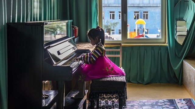 Một bé gái mặc trang phục truyền thống chơi piano tại trường mầm non Chongnam ở Chongjin.
