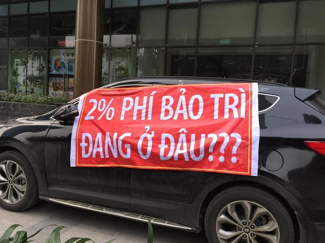Người dân treo băng rôn trên hàng loạt xe ôtô đỗ dưới chân toà nhà.