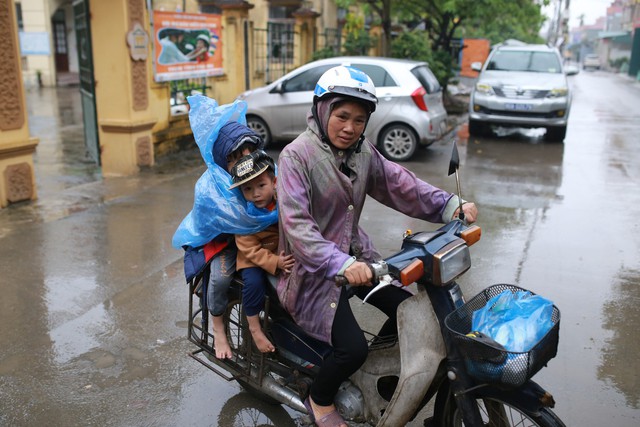 
Người dân Thuận Thành, Bắc Ninh đội mưa đưa con em đi xét nghiệm sán lợn miễn phí tại trường mầm non.
